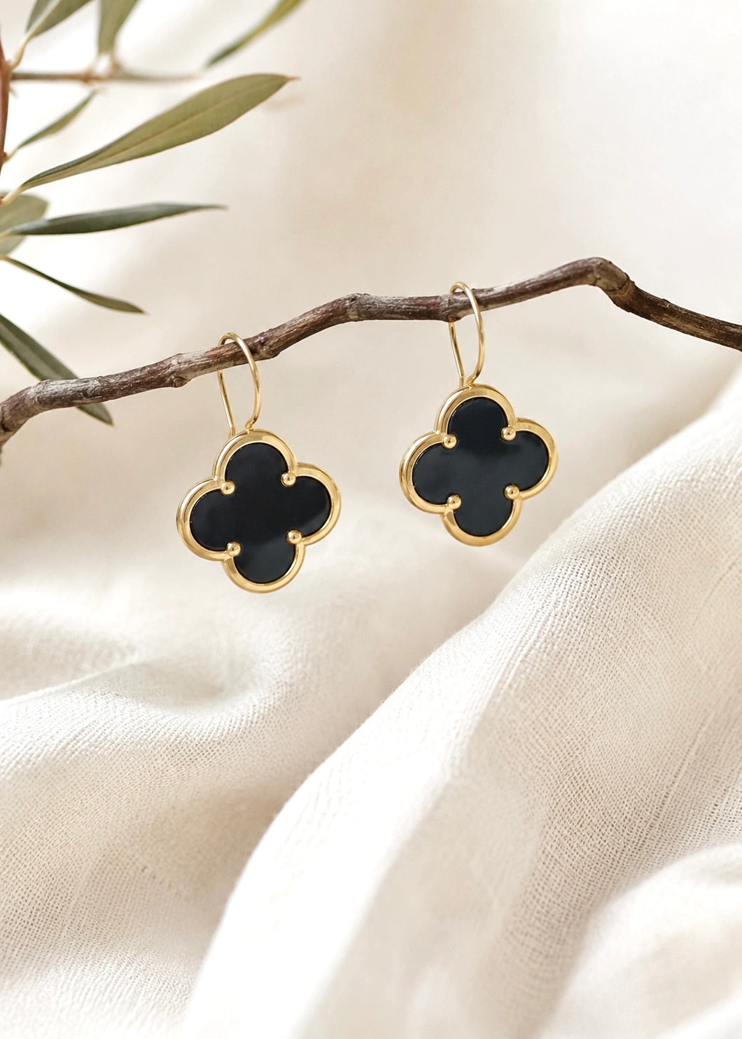Detail of four-leaf clover drop earrings with natural black onyx