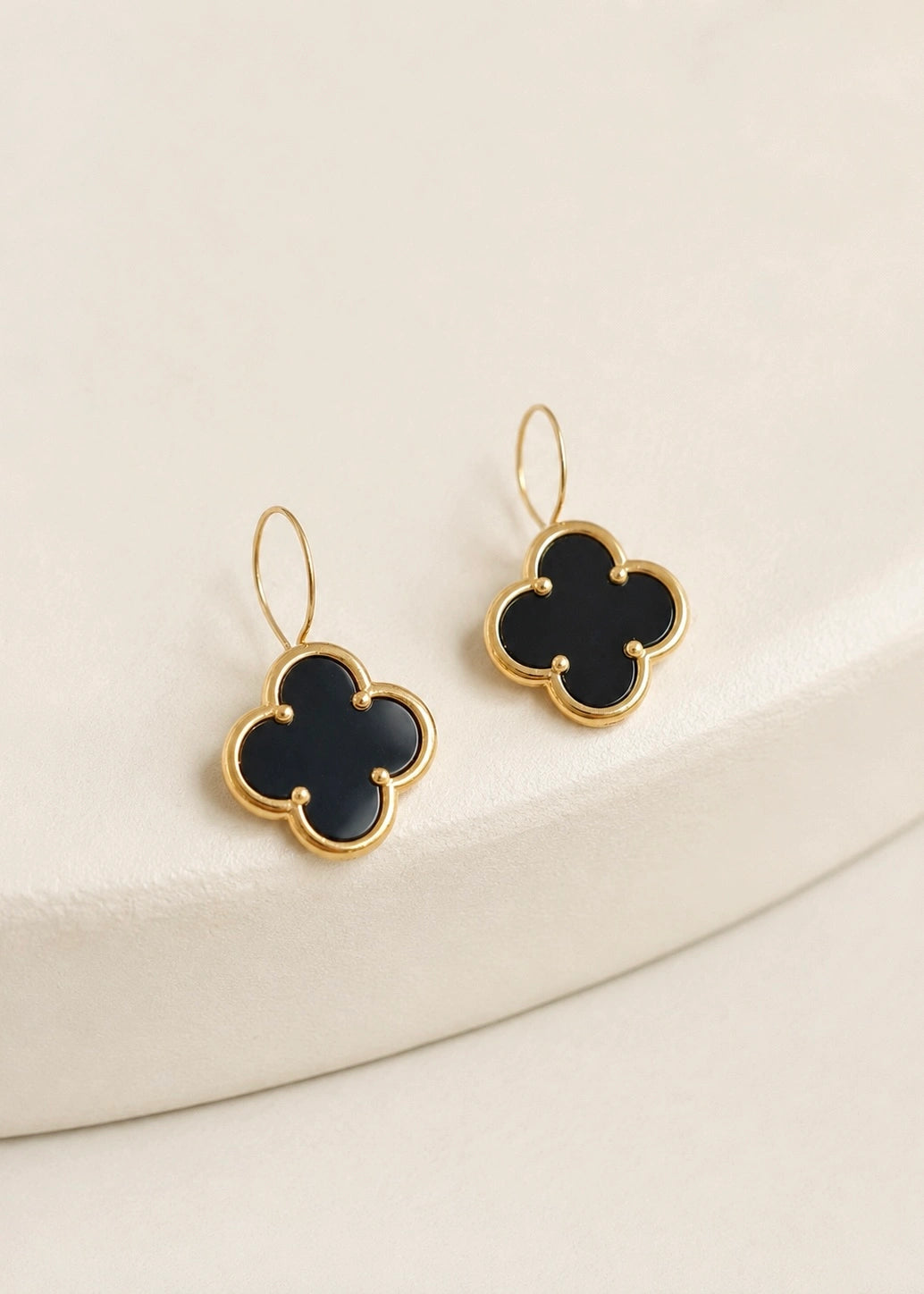 Black onyx four-leaf clover drop earrings worn on the ear