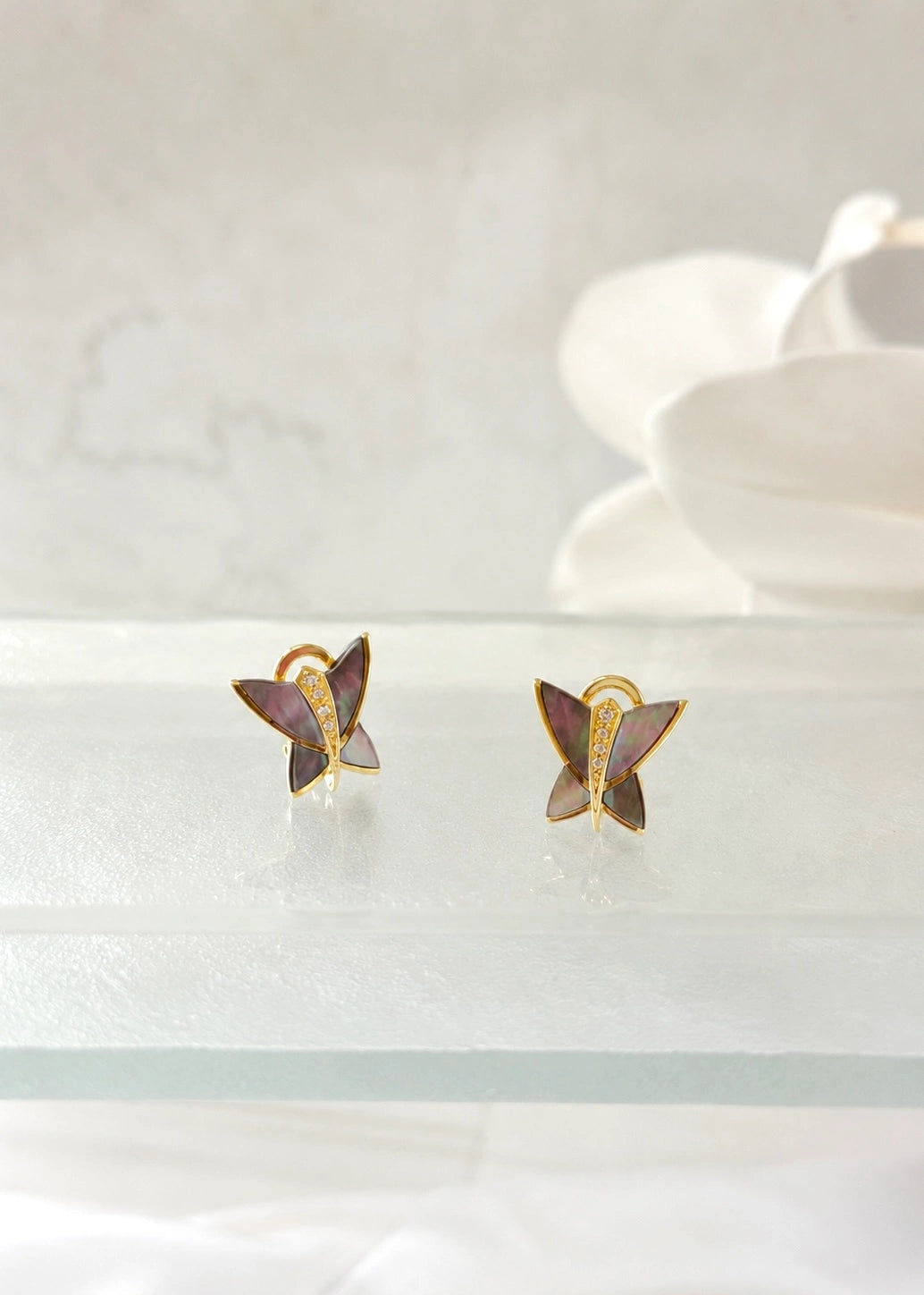 Close-up of an iridescent mother of pearl butterfly earring worn on the ear