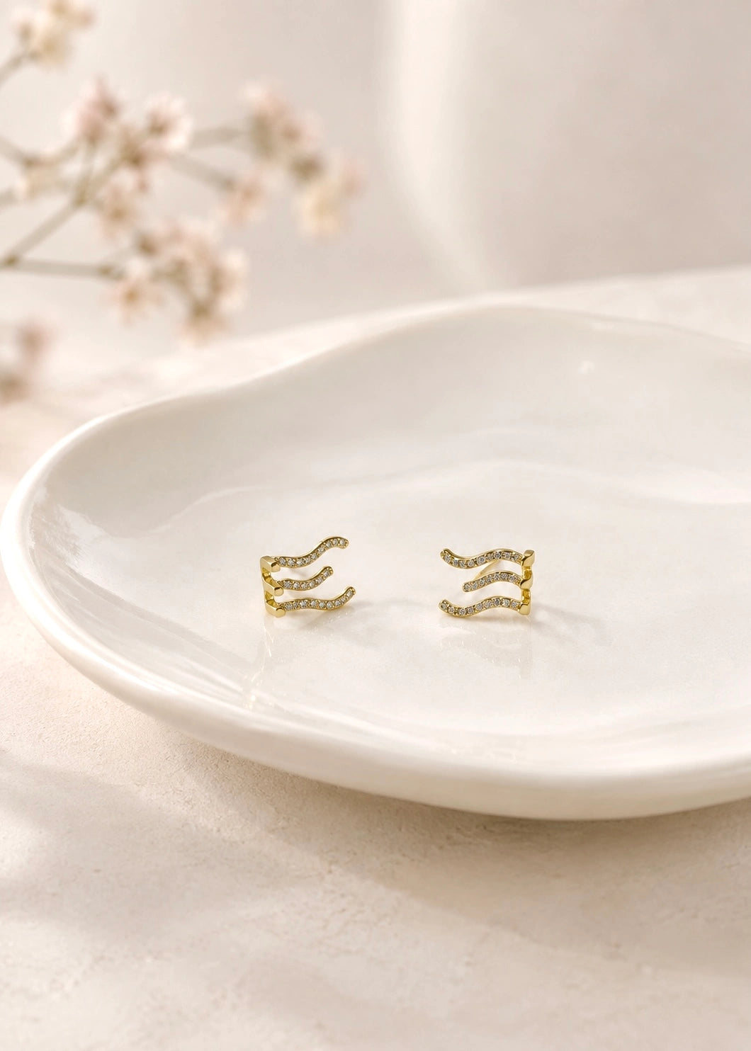 Wave earring with three curved lines and white zircons worn on the ear
