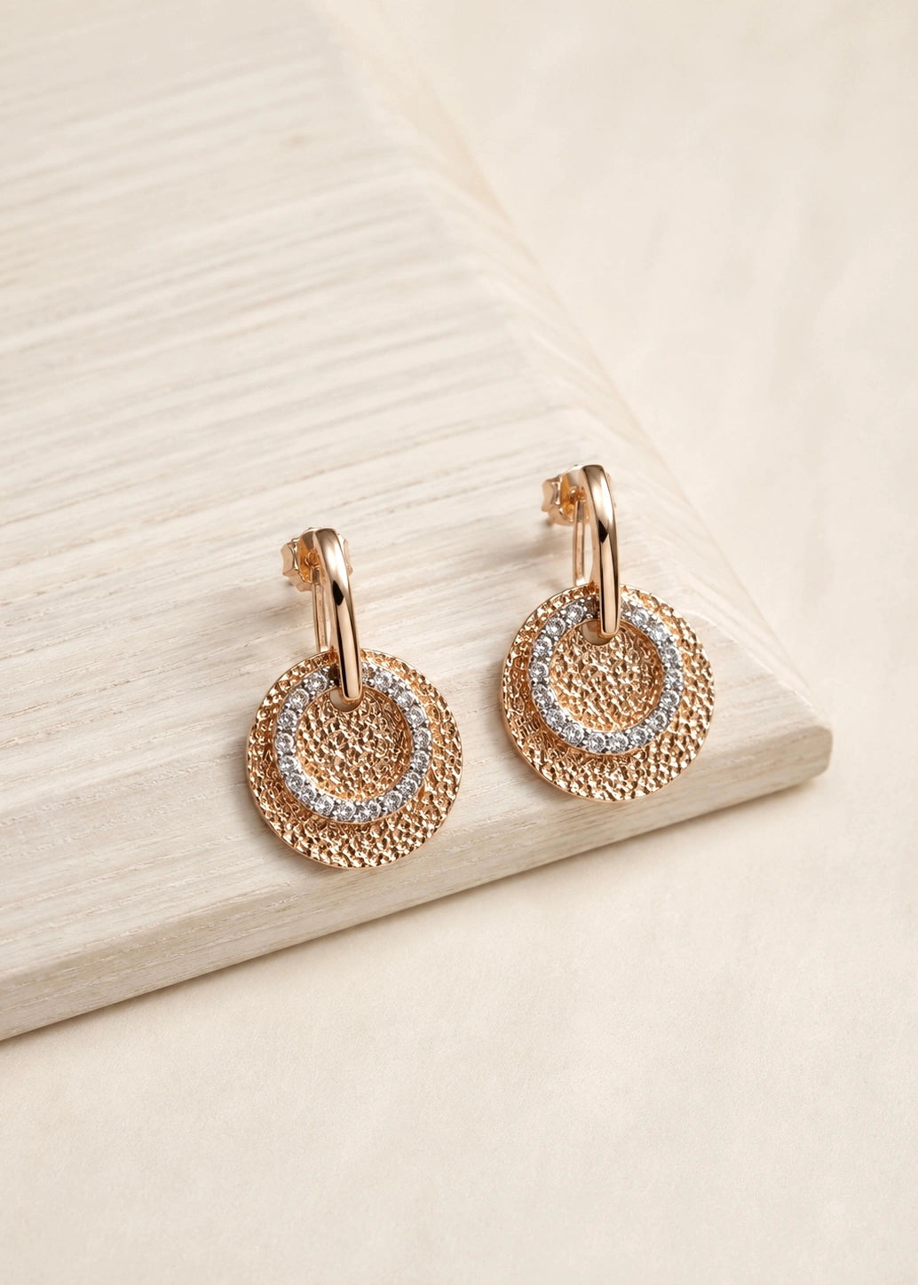 Bronze-tone earrings with a textured disc and white zircons, close-up