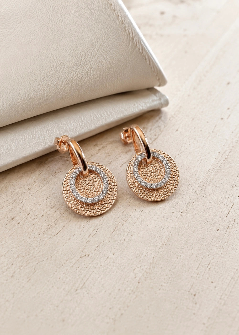 Textured bronze-tone disc earrings with white zircons worn on the ear