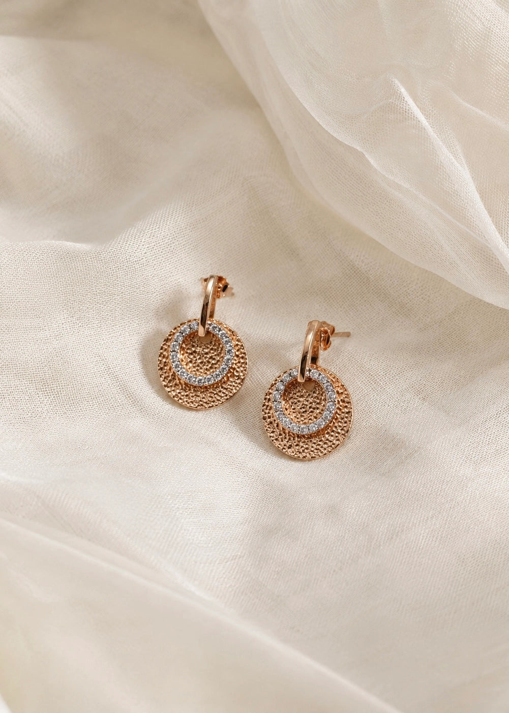 Close-up of bronze-tone earrings with white zircons worn on the ear