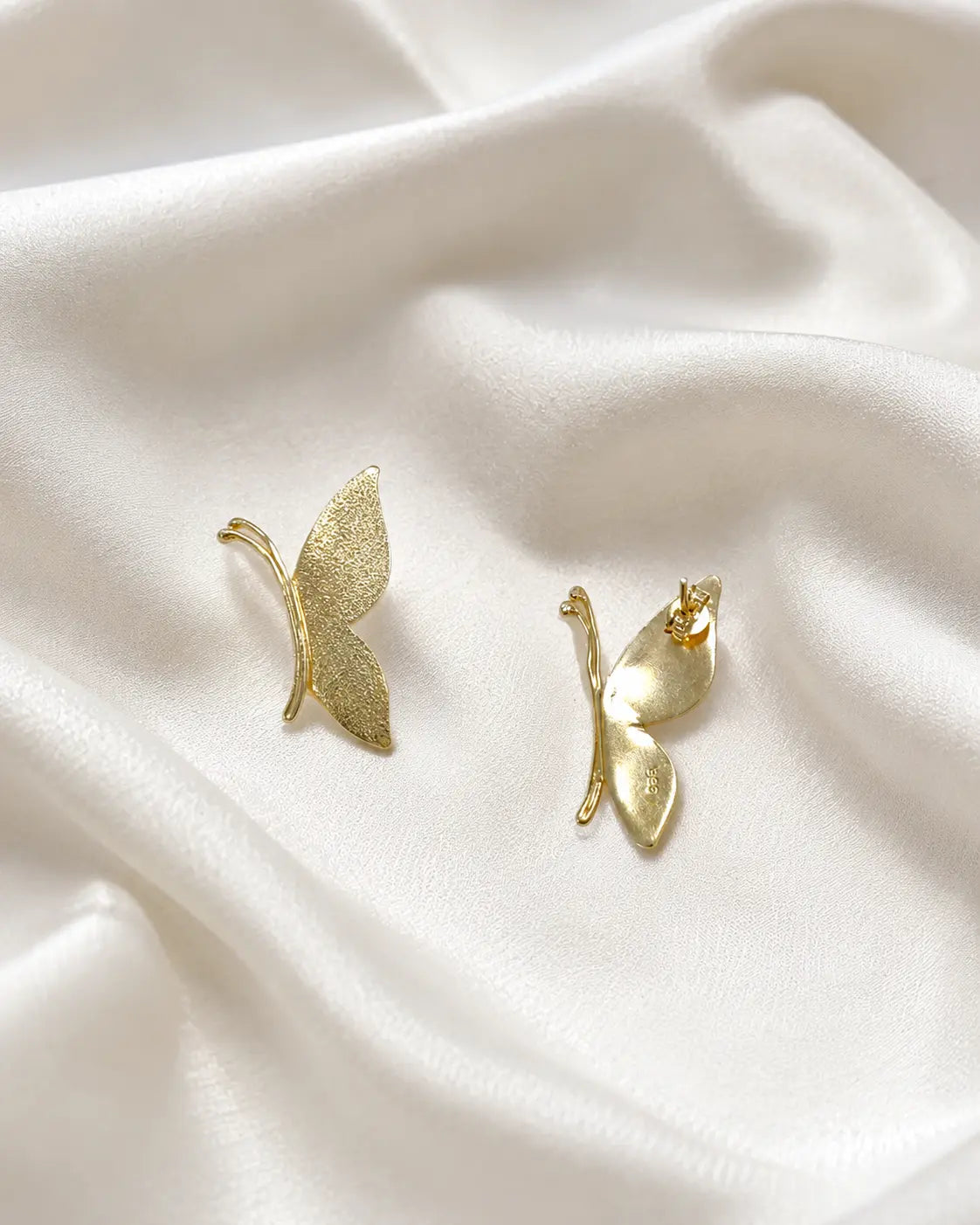 Close-up of slim gold-tone butterfly earrings