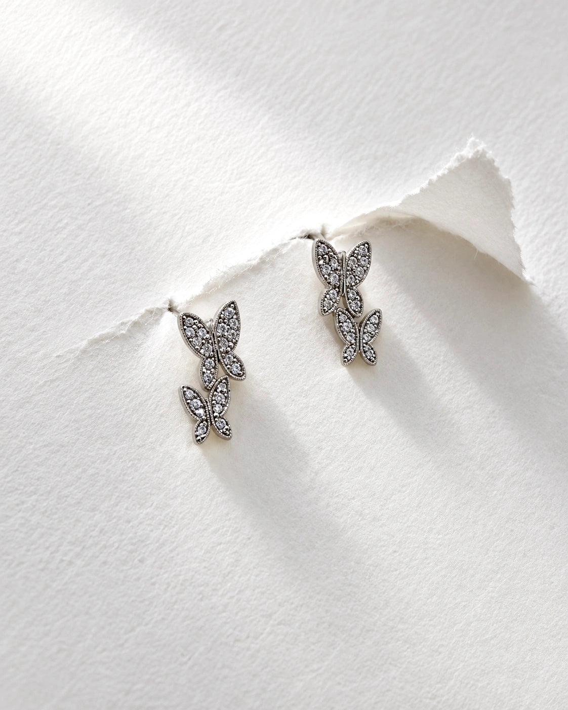 Close-up of a double butterfly earring with white zircons and a fine beaded border