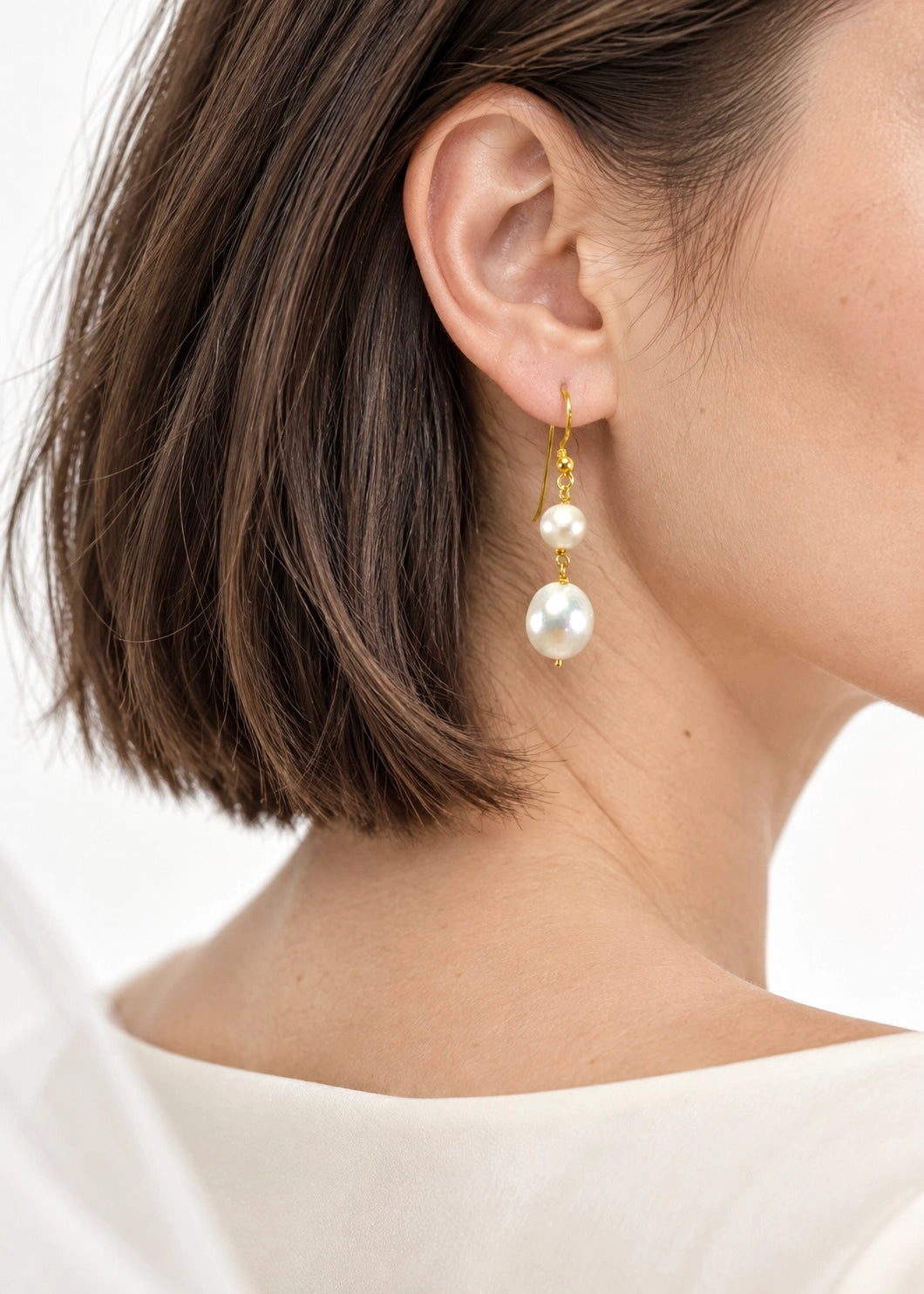 Natural pearl drop earrings worn on a woman's ear