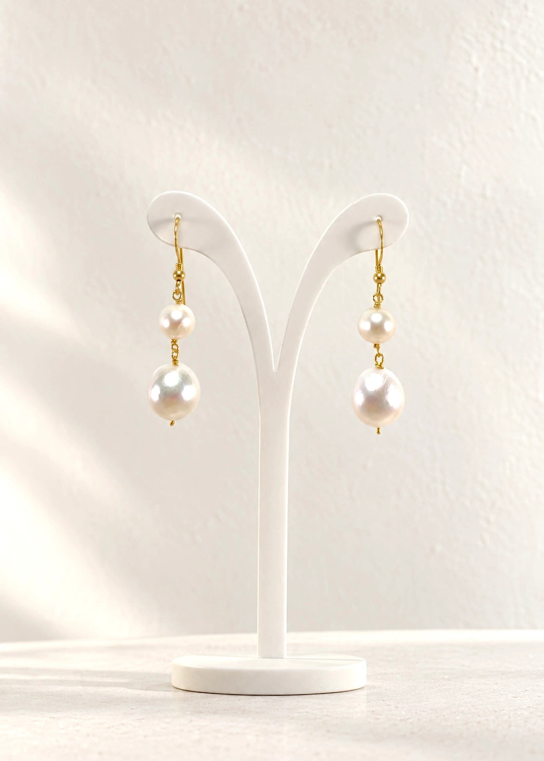 Natural white pearl drop earrings in gold-plated sterling silver 925 on a minimal stand