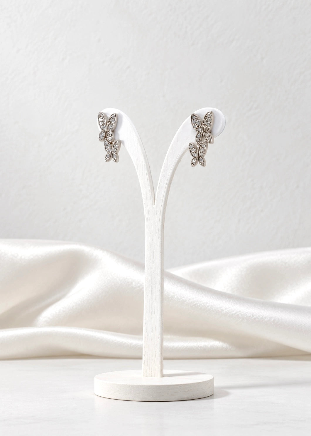 Pair of sterling silver double butterfly earrings with zircons on a second stand