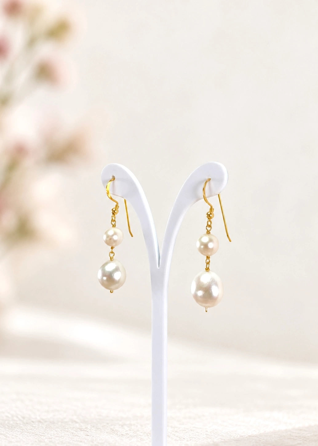 Natural pearl drop earrings in gold-plated sterling silver 925 on a second minimal stand