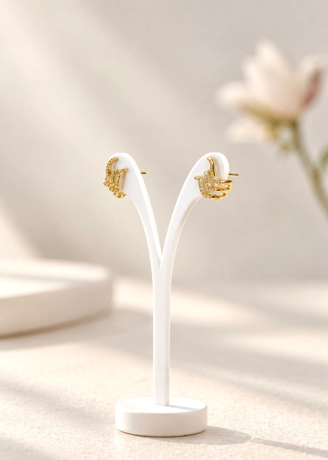 Close-up of gold-plated wave earrings with white zircons