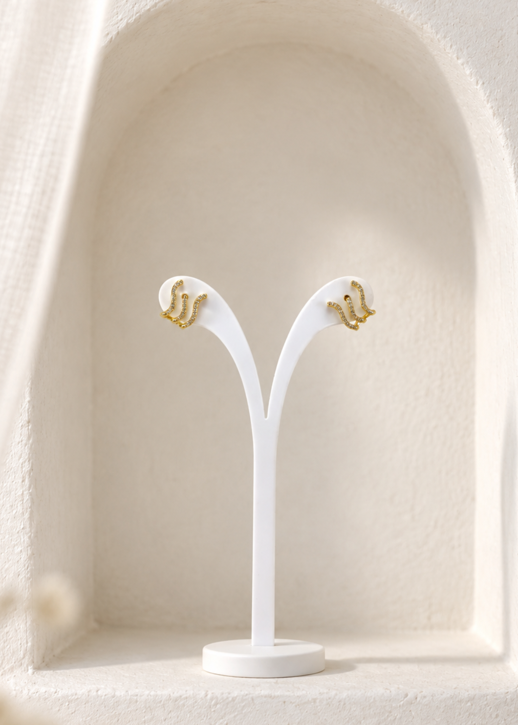 Gold-plated 925 sterling silver wave earrings with white zircons on a display stand