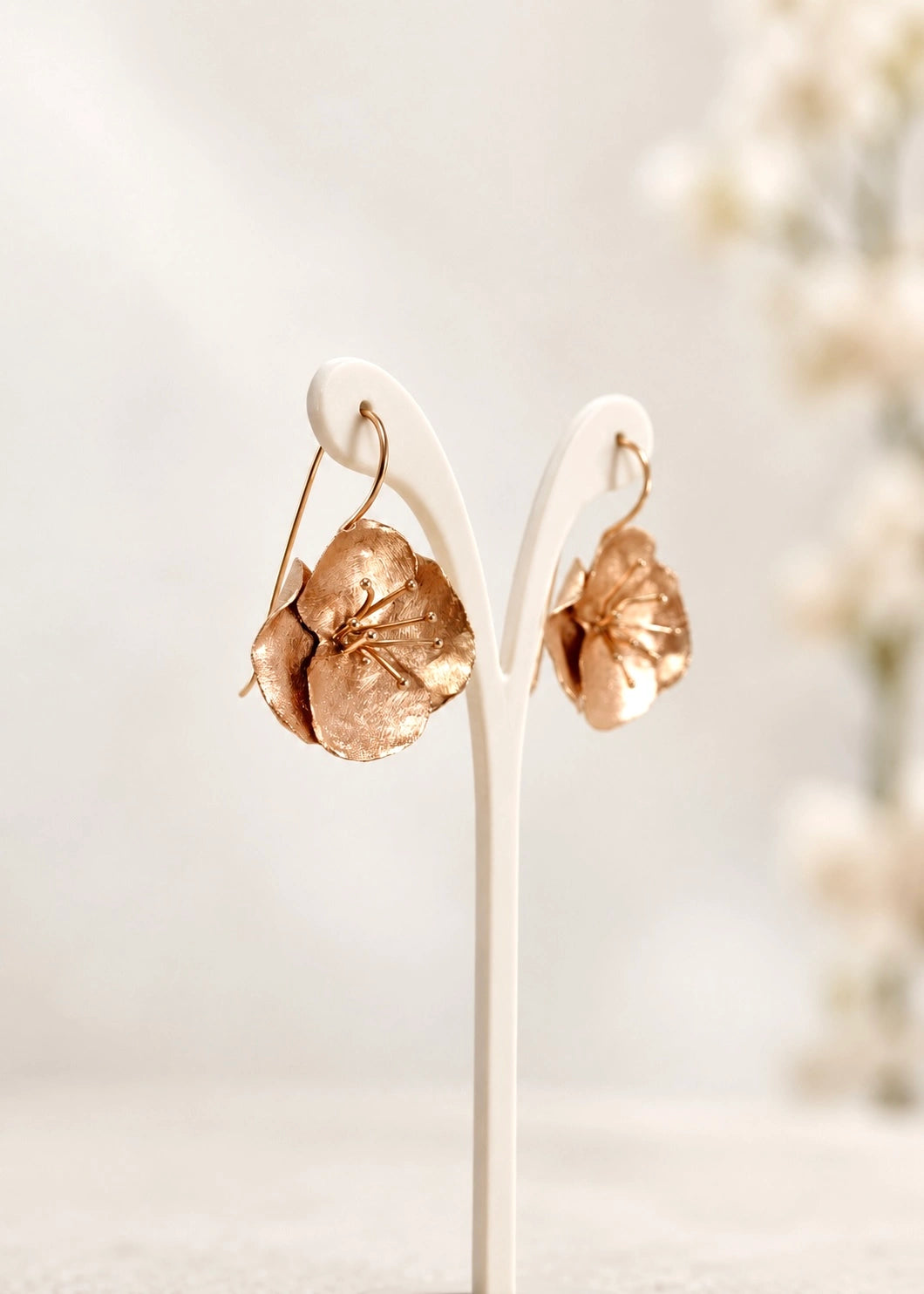 Flower drop earrings with textured petals on a display stand