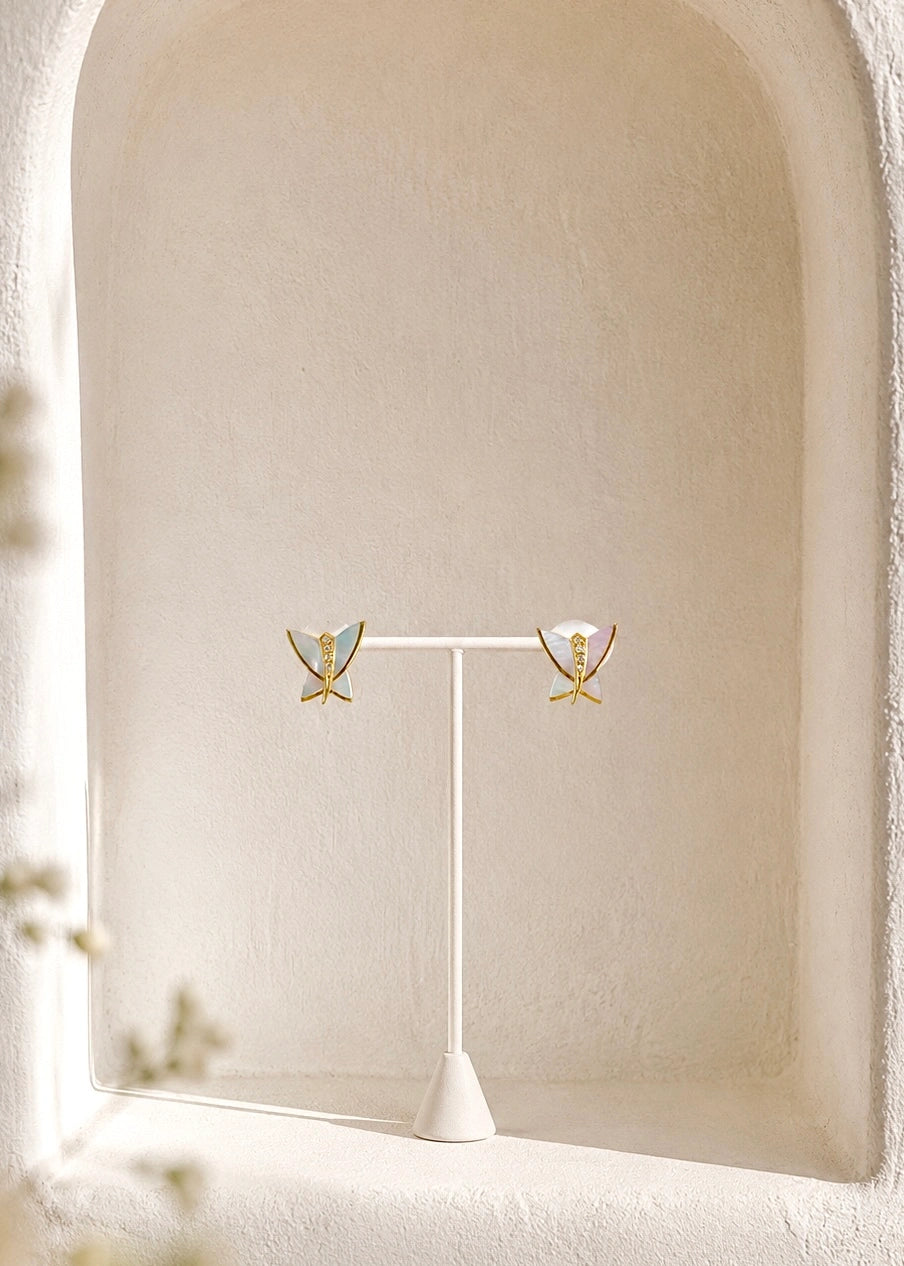 Pair of white mother of pearl butterfly earrings on a display stand