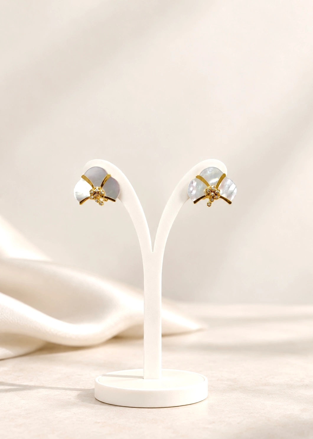 Gold-plated sterling silver earrings with white mother of pearl and zircons on a display stand