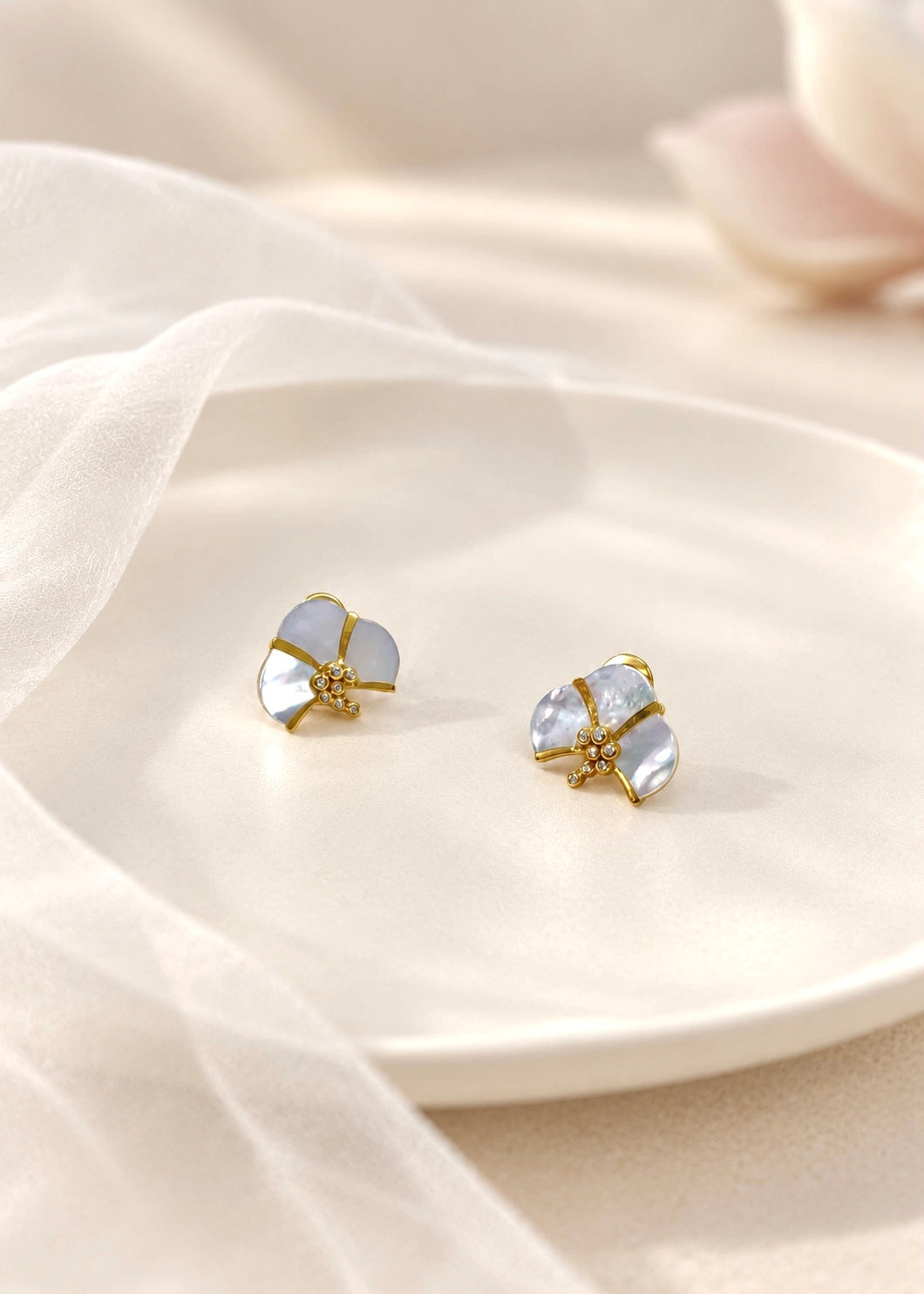 White mother of pearl and zircon earrings worn on the ear, close-up