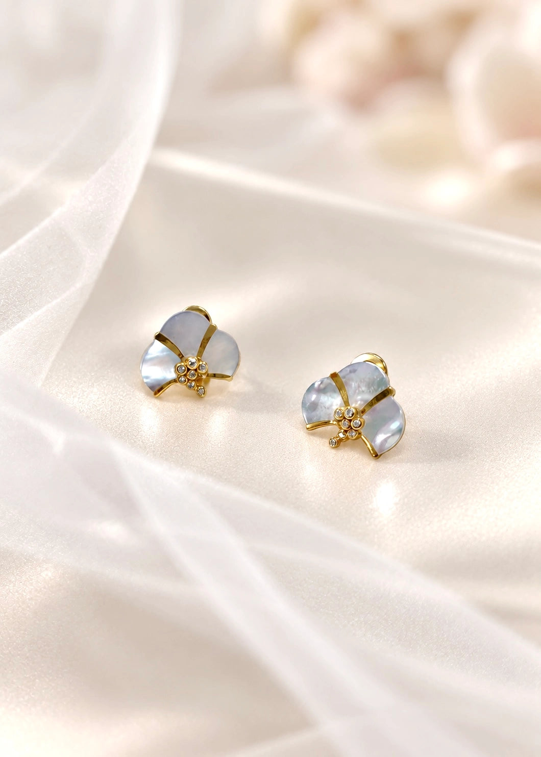 White mother of pearl earring with pearlescent reflections and white zircons worn on the ear